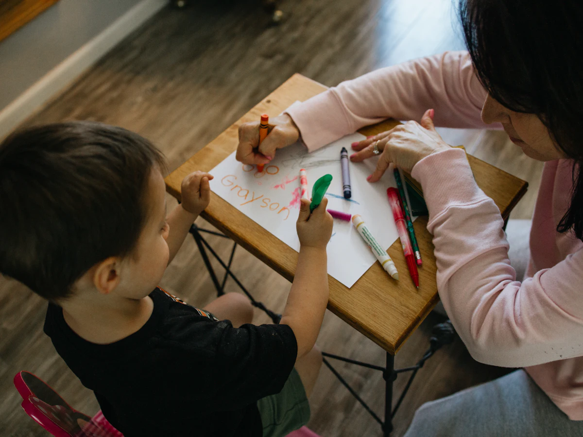 An adult and a young boy coloring together at a small table