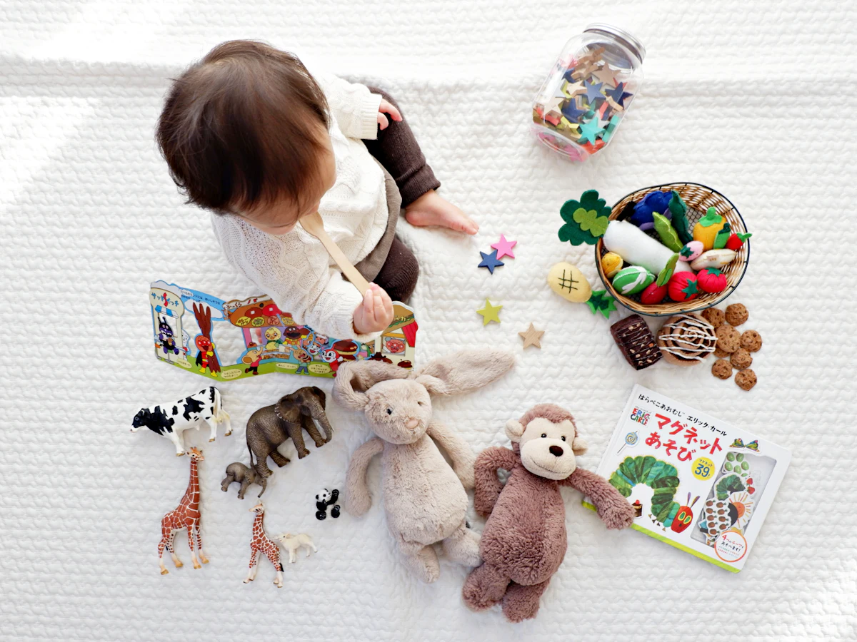 A toddler sitting among toys and picture books